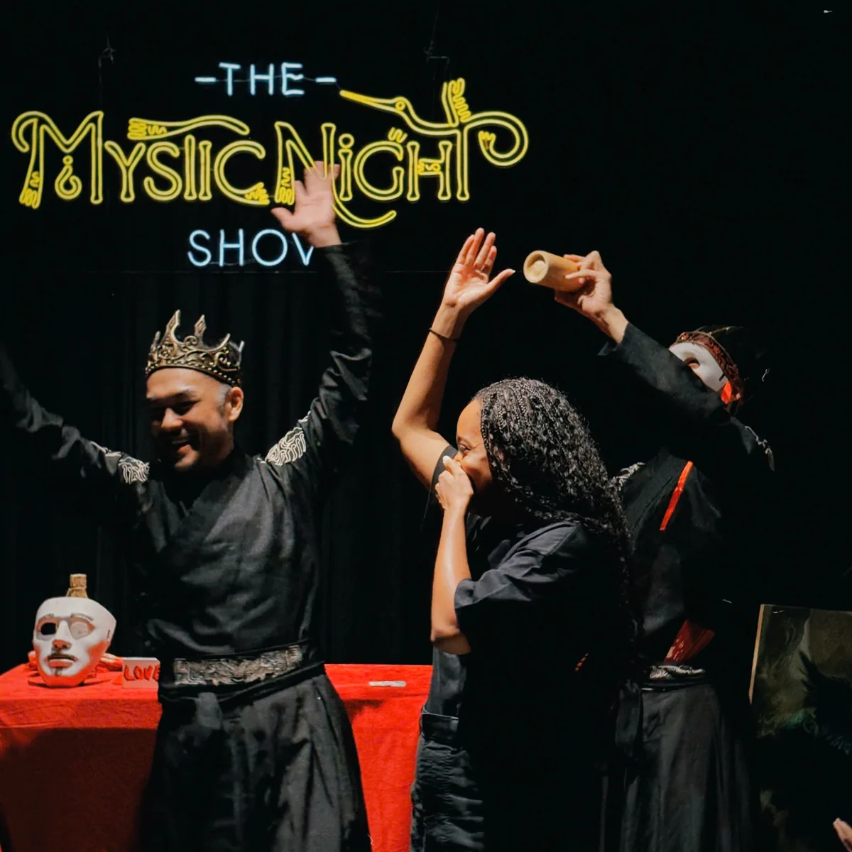 The Mystic Night Show magician and audience beneath the show’s illuminated sign; a date-neutral performance photo.