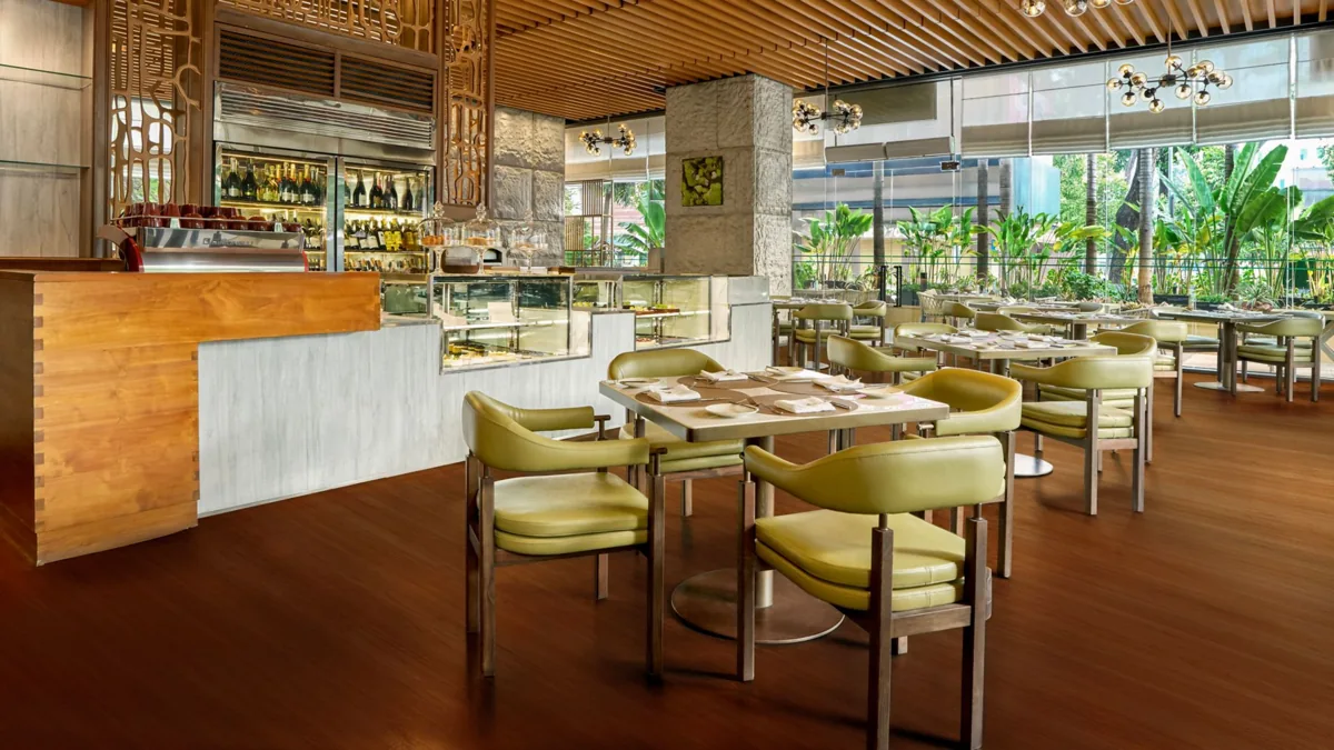 Dining room at Basilico in JW Marriott Hotel & Suites Saigon, with set tables and garden-facing windows.
