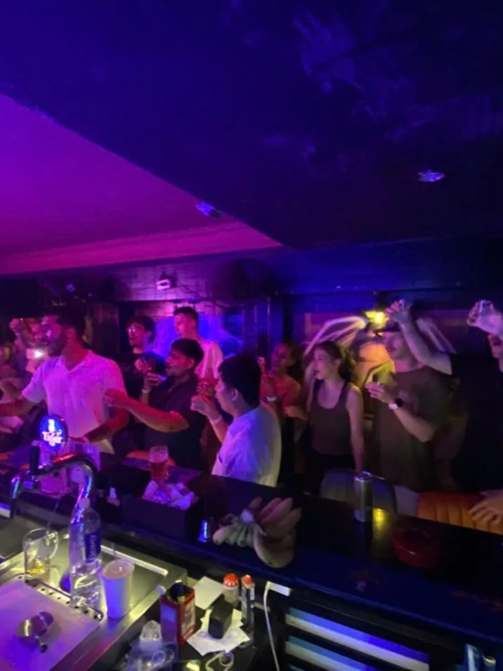 People at The Hideout Bar during the 24 October pub crawl; organizer schedule also appears in the caption.